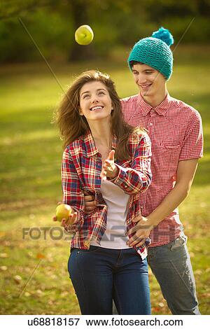 Teenage couple juggling apples in park View Large Photo Image Stock Photo - Teenage couple juggling apples in park. Fotosearch