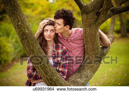 Picture - Teenage couple kissing in tree in park. Fotosearch