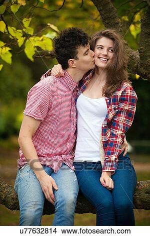 Teenage couple kissing in tree in park View Large Photo Image Picture - Teenage couple kissing in tree in park. Fotosearch