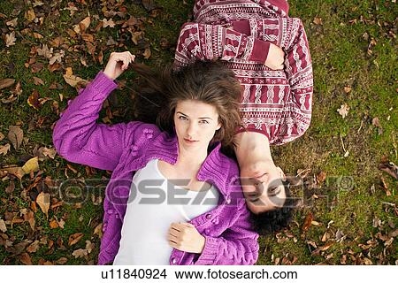 Teenage couple laying in grass in park View Large Photo Image Picture - Teenage couple laying in grass in park. Fotosearch