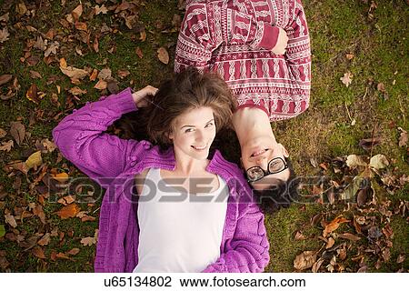 Stock Image - Teenage couple laying in grass in park. Fotosearch