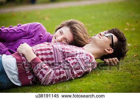 Teenage couple laying in grass in park View Large Photo Image Stock Photography - Teenage couple laying in grass in park. Fotosearch