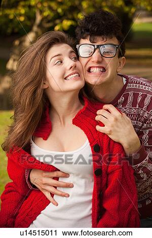 Stock Image - Teenage couple making faces in park. Fotosearch