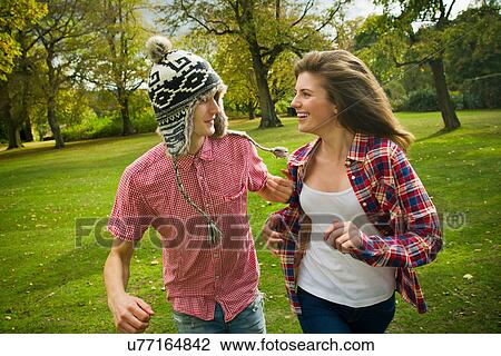 Stock Image - Teenage couple running in park. Fotosearch