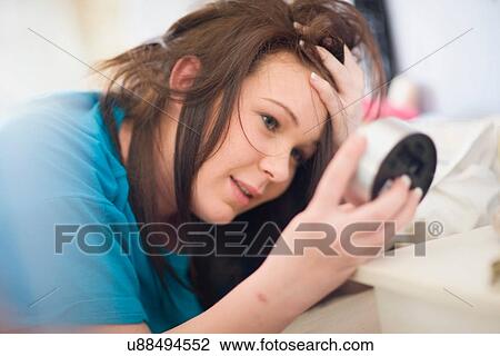Teenage girl checking alarm clock View Large Photo Image Stock Image - Teenage girl checking alarm clock. Fotosearch