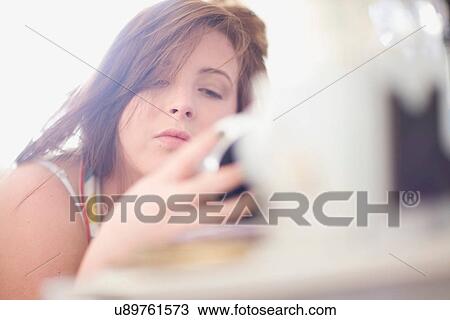 Stock Image - Teenage girl checking alarm clock. Fotosearch