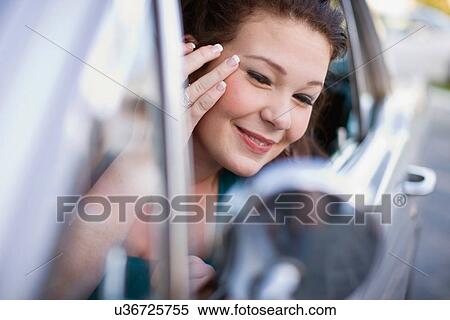 Stock Photography - Teenage girl checking makeup in car. Fotosearch