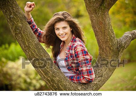 Stock Photograph - Teenage girl climbing tree in park. Fotosearch