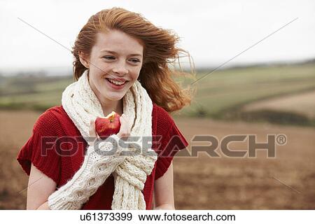 Teenage girl eating apple in field View Large Photo Image Stock Photo - Teenage girl eating apple in field. Fotosearch