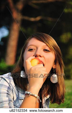 Teenage girl eating fruit in backyard View Large Photo Image Picture - Teenage girl eating fruit in backyard. Fotosearch