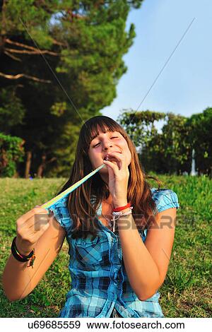 Stock Photo - Teenage girl eating in backyard. Fotosearch
