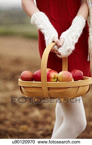 Stock Image - Teenage girl holding basket of apples. Fotosearch