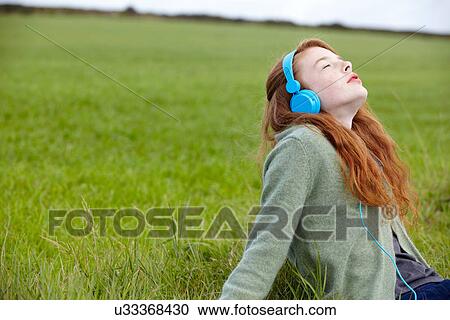 Stock Image - Teenage girl listening to headphones. Fotosearch