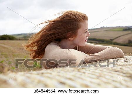 Picture - Teenage girl resting on haybale. Fotosearch
