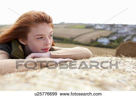 Stock Photo - Teenage girl resting on haybale. Fotosearch