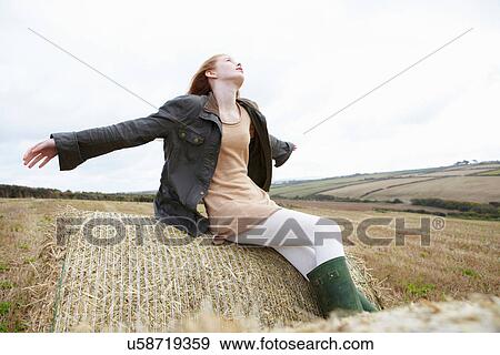 Stock Photo - Teenage girl resting on haybales. Fotosearch