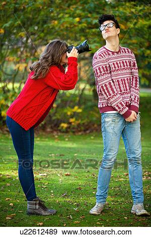 Stock Photo - Teenage girl taking picture of boyfriend. Fotosearch