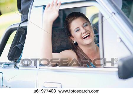 Stock Image - Teenage girl waving from car. Fotosearch