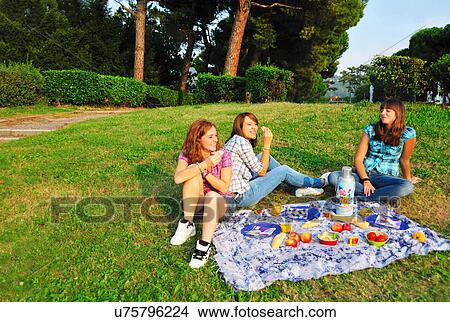 Picture - Teenage girls picnicking in rural field. Fotosearch