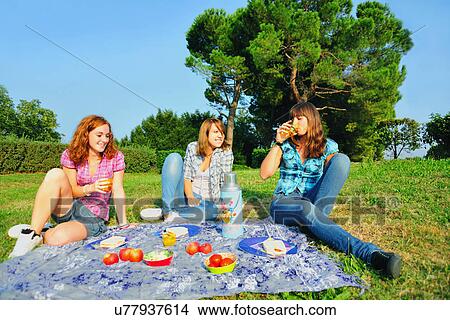 Picture - Teenage girls picnicking in rural field. Fotosearch
