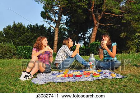 Teenage girls picnicking in rural field View Large Photo Image Stock Image - Teenage girls picnicking in rural field. Fotosearch