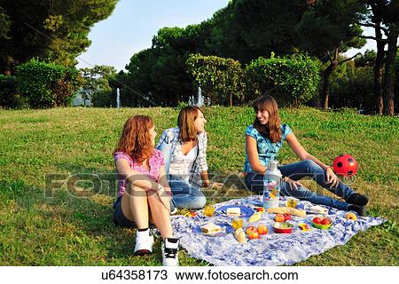 Stock Image - Teenage girls picnicking in rural field. Fotosearch