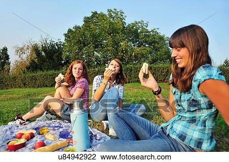 Teenage girls picnicking in rural field View Large Photo Image Stock Image - Teenage girls picnicking in rural field. Fotosearch