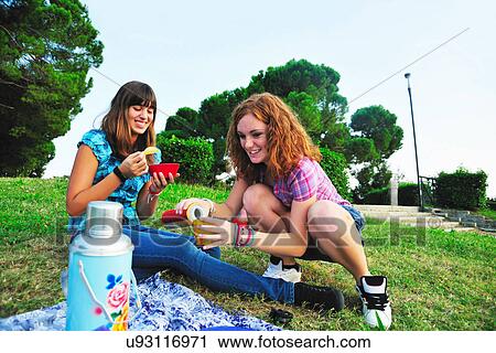 Stock Image - Teenage girls picnicking in rural field. Fotosearch