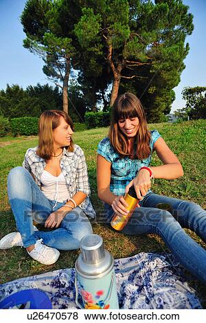 Teenage girls picnicking in rural field View Large Photo Image Stock Photo - Teenage girls picnicking in rural field. Fotosearch