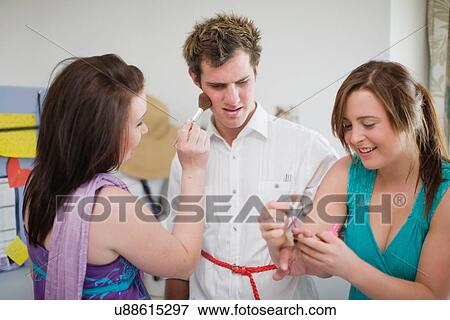 Teenage girls putting makeup on boy View Large Photo Image Stock Photo - Teenage girls putting makeup on boy. Fotosearch