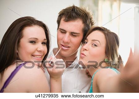 Stock Photography - Teenage girls putting makeup on boy. Fotosearch