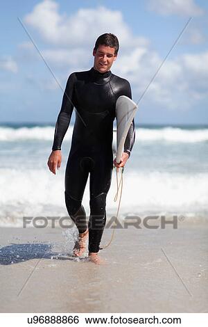 Stock Photograph - Teenage surfer carrying board on beach. Fotosearch