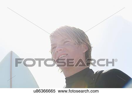 Teenage surfers carrying board on beach View Large Photo Image Stock Photography - Teenage surfers carrying board on beach. Fotosearch