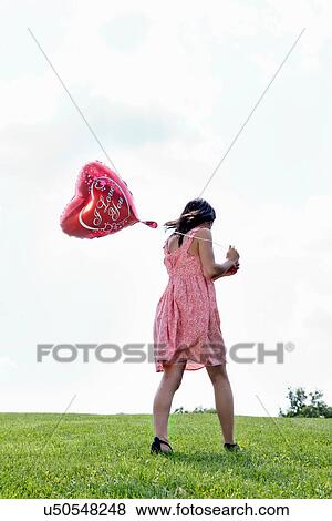 Stock Photo - Teenager carrying heart-shaped balloon. Fotosearch