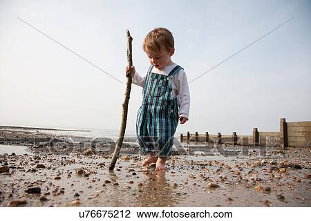 Stock Image - Toddler playing with stick on beach. Fotosearch