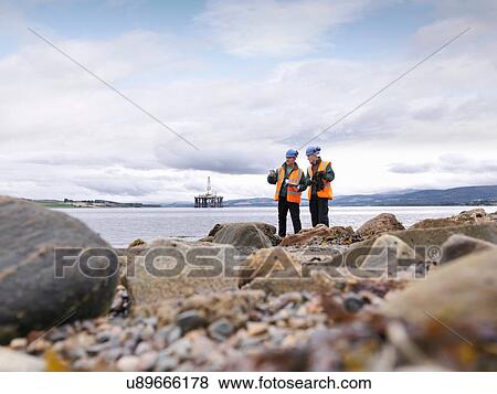 Stock Photo - Two male environmentalists checking samples on seashore. Fotosearch
