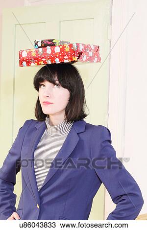 Stock Image - Woman balancing Christmas presents. Fotosearch