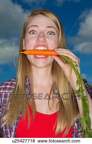 Woman biting carrot outdoors View Large Photo Image Stock Photo - Woman biting carrot outdoors. Fotosearch