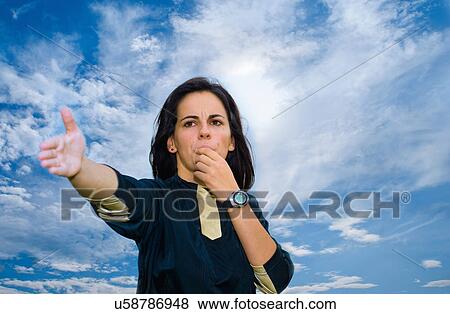 Stock Photo - Woman blowing whistle against blue sky. Fotosearch