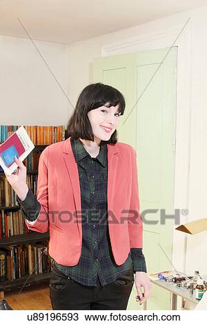 Stock Image - Woman carrying passport in living room. Fotosearch