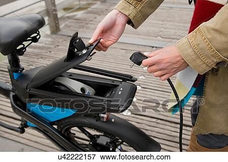 Woman charging electric bike outdoors View Large Photo Image Stock Photo - Woman charging electric bike outdoors. Fotosearch