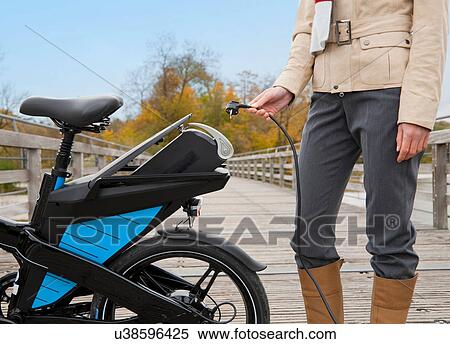 Woman charging electric bike outdoors View Large Photo Image Stock Photography - Woman charging electric bike outdoors. Fotosearch