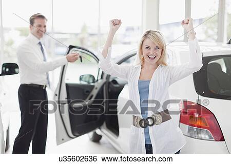 Stock Photograph - Woman cheering in car dealership. Fotosearch