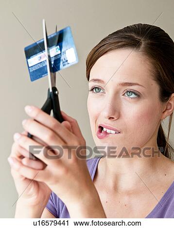 Stock Image - Woman cutting up credit card. Fotosearch