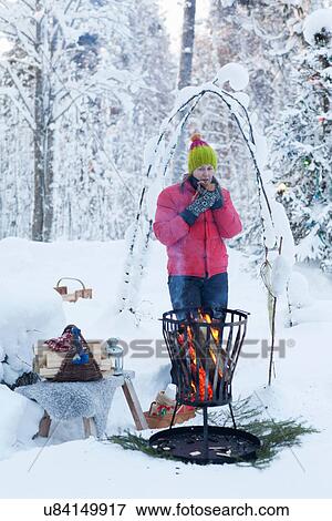 Woman drinking coffee by firepit in snow View Large Photo Image Stock Photo - Woman drinking coffee by firepit in snow. Fotosearch