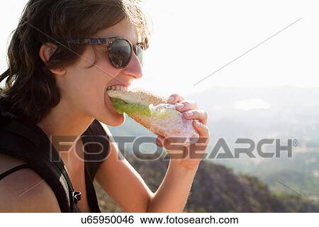 Stock Photograph - Woman eating sandwich outdoors. Fotosearch