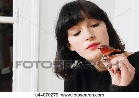 Stock Photo - Woman examining bird figurine. Fotosearch