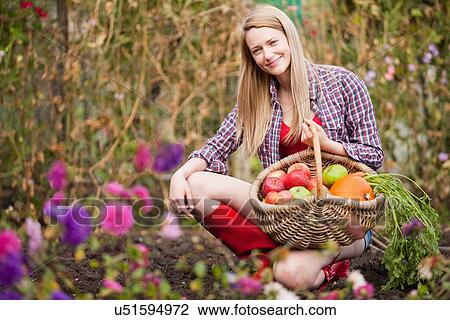 Stock Image - Woman gathering vegetables in garden. Fotosearch