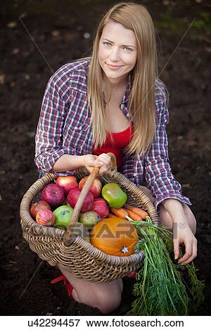 Woman gathering vegetables in garden View Large Photo Image Stock Photo - Woman gathering vegetables in garden. Fotosearch