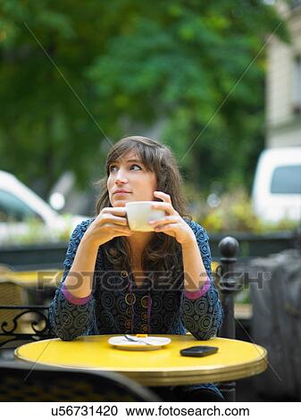 Stock Image - Woman having coffee at sidewalk cafe. Fotosearch